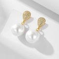 Macro view of gold-plated drop earrings with sparkling zircon and large white pearls - 925 Silver / Gold