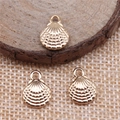 Macro view of three gold alloy shell pendants on a wooden background for jewelry making - KC Gold