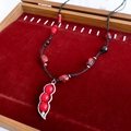Detaillierte Flachbildaufnahme einer Vintage-Halskette mit rotem Bohnenanhänger auf Samt - Vintage Einfacher Stil (Schwarz-Rot)