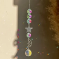 Close-up of crystal prism suncatcher reflecting rainbow light with silver moon and star charms - Moon Hugging Star Pentagram