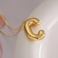 Golden balloon-style letter C pendant necklace with a polished metallic finish - Letter C