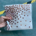 White disposable napkins with rose gold polka dots in transparent packaging held by hand - Rose Gold Dots Napkins x24