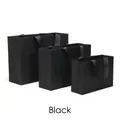 Three sizes of matte black paper gift bags with elegant black ribbon handles - Black