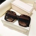 Detail of square oversized tortoise shell sunglasses with gradient brown lenses on a box - Leopard Frame Gradient Brown Lens