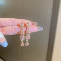 Detailaufnahme der goldenen Ohrhänger mit funkelnden rosa Kristallen und Glanzeffekt - Rosa Strass Geometrische Tropfenohrringe