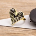 Anillo de corazón dorado con esmalte negro sobre fondo de madera natural - Negro