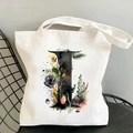 Detailed close-up of a white canvas tote bag with a floral letter I print on a black chair - Letter I / 35*40cm