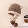 Dettaglio del cappello di peluche con paraorecchie, maglia morbida e pompon marroni soffici - 3-8 Anni / Marrone