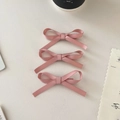 Vue détaillée de 3 barrettes à nœuds en satin rose sur une surface claire épurée - Ensemble de 3 / Rose Fille