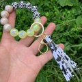 Close-up of cow print silicone bead bracelet keychain with iridescent beads and tassel - Black and White Leopard Print