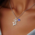 Silver flower pendant necklace with blue gemstone on model neck for December birthday - September