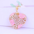 Portachiavi a cuore dorato con rose in smalto rosa e cristalli scintillanti su sfondo bianco - Rosa