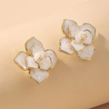 Gros plan de boucles d'oreilles camélia avec émail blanc et bordures dorées - Camélia Blanc (Tige en Argent)
