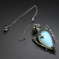 Detailed macro shot of vintage silver flower frame with a blue opal stone pendant - Opal + Pendulum Chain