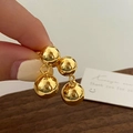 Primer plano detallado de pendientes de bola dorados pulidos con diseño colgante doble - Pendientes de Bola Doble Grandes Dorados
