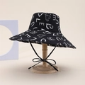 Reversible bucket hat with black graffiti print and adjustable chin strap on wood stand - Letter Style / Black