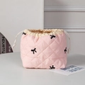 Detailed view of pink quilted cosmetic bag with black embroidered bows and drawstring closure - Embroidered Bow Pink