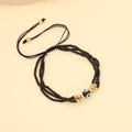 Detailansicht eines mehrlagigen Perlenarmbands mit Goldakzenten und Evil Eye Charm - Schwarz