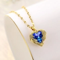 Primer plano macro de colgante de corazón con gema azul y alas doradas brillantes - Azul Real Degradado / Cadena de Oro