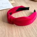 Close-up of a knotted rose red velvet headband with a wide design on a wooden background - Red Velvet Headband