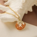 Golden seashell pendant necklace with orange enamel, starfish and pearl detail on white background - Enamel Starfish Pearl Style / Orange