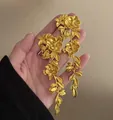 Orecchini vintage in oro opaco con fiori e nappe lunghe tenuti in mano - Stile Fiore Oro (17#)