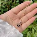 Detalle del collar chapado en oro de 18K con colgante de lazo negro y cuentas de metal - Negro