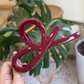 Detail of burgundy large bow hair claw clip featuring sleek glossy finish and metal spring - Ancorra Red