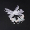 Detail eines Blumen-Haarreifens mit weißen Organza-Bändern und Perlen auf Schwarz - Handgelenk-Corsage / Blau