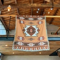 Detail of bohemian woven blanket with geometric patterns and fringe on wooden railing - Seattle Orange Brown Ethnic Geometric