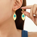 Elegant gold leaf earrings with turquoise center on model in warm studio lighting - Golden Leaf Turquoise