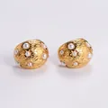 Detailed shot of gold-plated earrings with hammered texture, pearls, and star accents - Amleh007