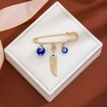 Detail of gold brooch with blue evil eye beads and a golden feather in a white gift box - Feather Pendant Style (Z102-1)
