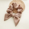 Primer plano de scrunchie rosa con lazo y textura plisada sobre posavasos trenzado - Champaña