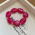 Macro detail of irregular pink acrylic beads with gold metal spacers on a display tray - Rose Red