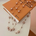 Elegante collana a catena in oro rosa con perle barocche rosa su un libro arancione - Stile Catena Dorata Con Perline Rosa