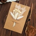 Handmade kraft card with preserved white dried flowers on dark wood background - Rainbow