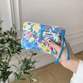 Hand holding floral fabric cosmetic pouch with blue woven drawstring and brand label - Tulip Blue