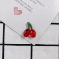 Close-up of a translucent red cherry pendant with a green stem on a white heart card - 2# (Red Translucent Cherry)