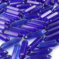 Translucent dark blue double-pointed hexagonal crystal pendants in a scattered pile - Transparent Blue