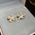 Dettaglio di orecchini a fiore con zirconi scintillanti e perle in una scatola regalo - Oro