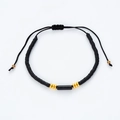 Dettaglio del bracciale in silicone nero con perla cilindrica e finiture dorate lucide - Nero