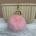 Pink faux rabbit fur pom-pom keychain with gold metal ring on a woven basket - Pink