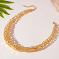 Close-up of golden interlocking geometric chain necklace with complex woven design - Gold
