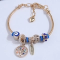 Gold snake chain bracelet with evil eye beads and tree of life love charms on white background - Blue
