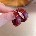 Detail of bold dark red enamel hoop earrings with polished finish and silver needles - Red