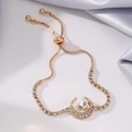 Macro detail of gold-plated moon and star charms on an adjustable slider bracelet - Star & Moon / Gold
