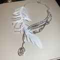 Elegante collana asimmetrica con piume e cristalli brillanti e un ciondolo a goccia - Piuma Bianca Argentata