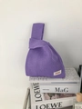 Chic purple knitted knot bag with hollow texture displayed on top of a laptop and books - Purple