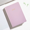 Pink A6 mini portable notebook with golden NOTES text on a professional desk setup - Violet
